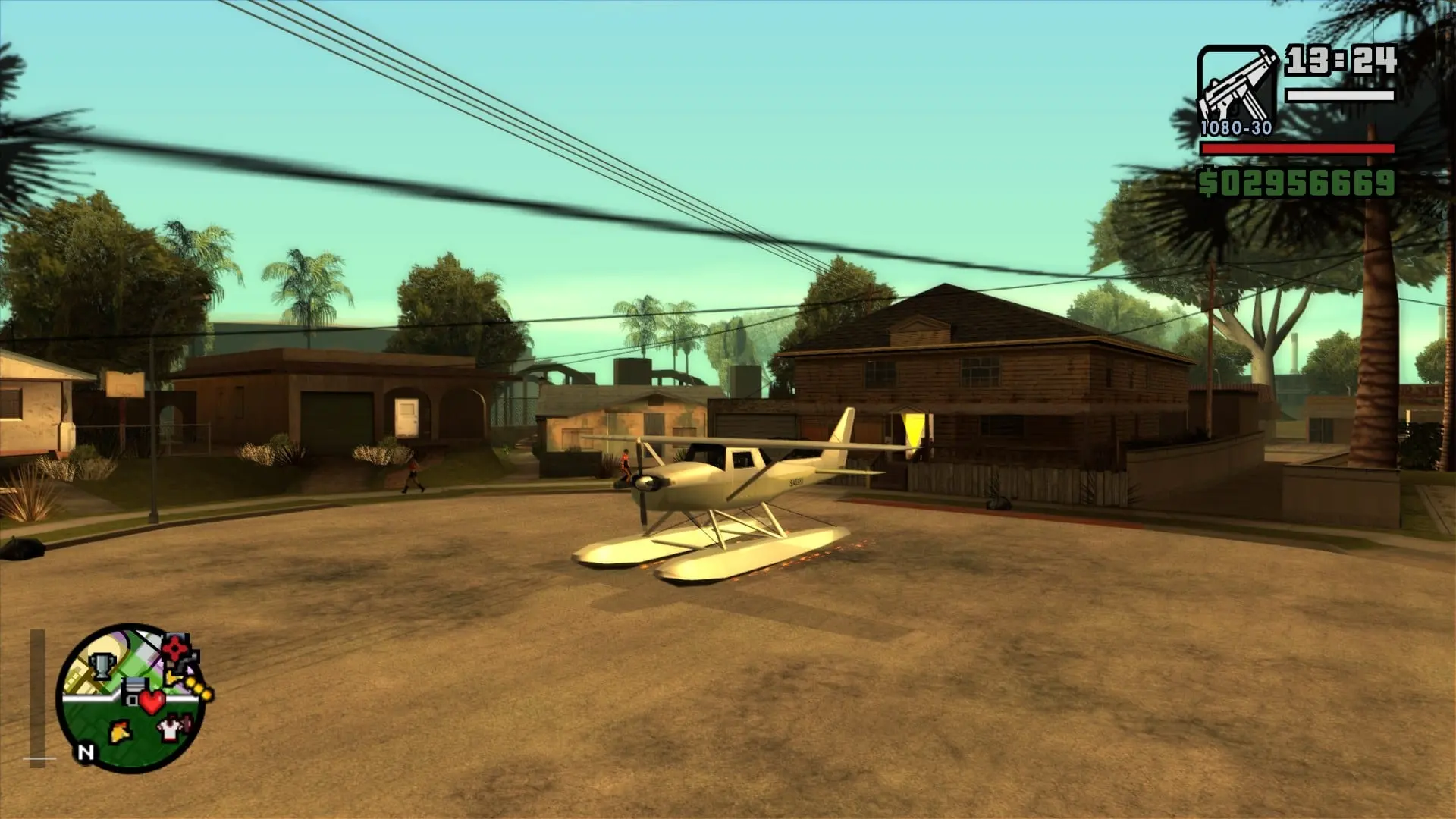 El hidroavión Skimmer, blanco con flotadores, aparcado en una calle de tierra de Los Santos en GTA San Andreas, junto a casas y palmeras.
