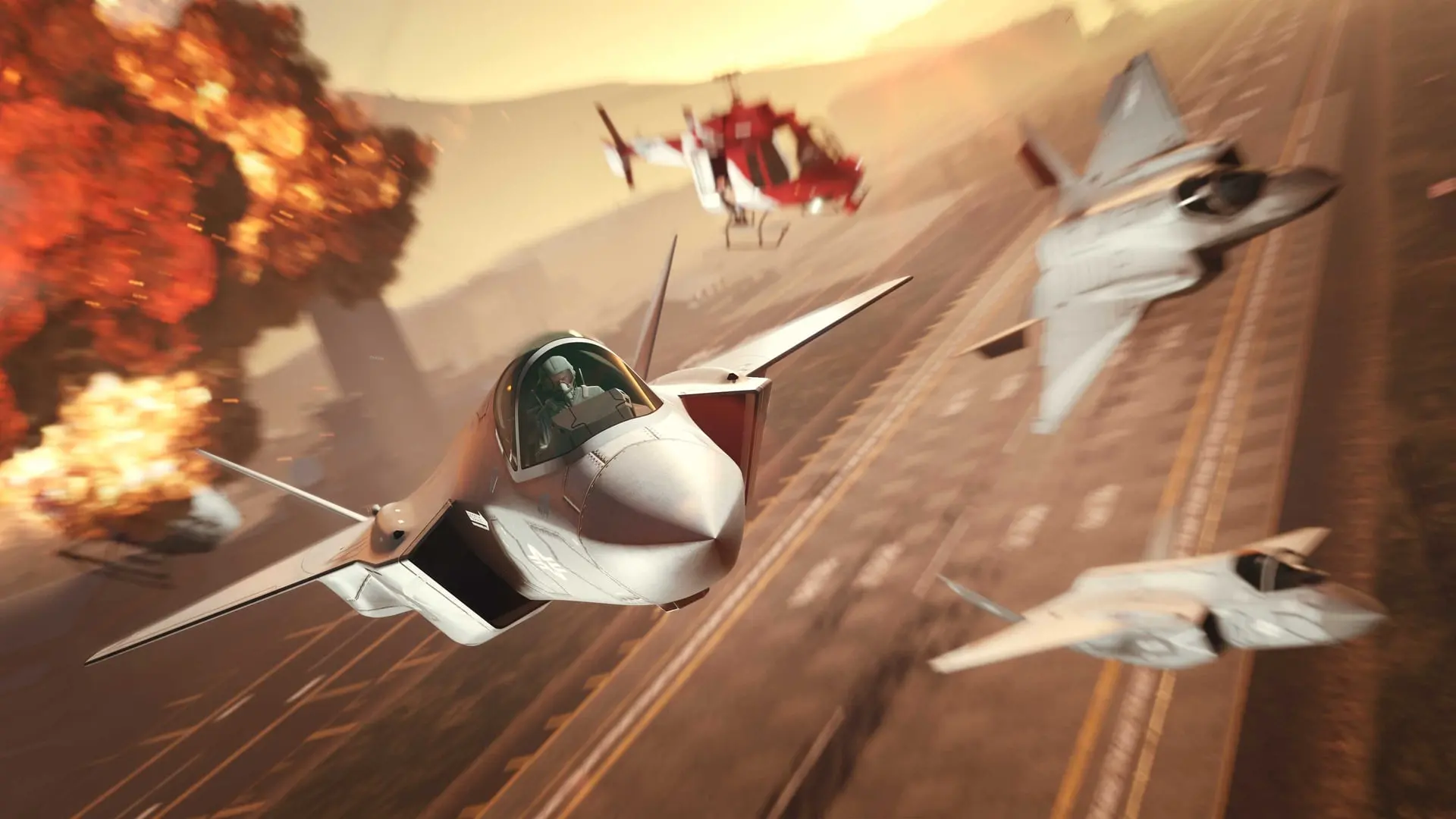 Three fighter jets flying low over a desert highway amid explosions with a helicopter behind them in GTA Online: San Andreas Mercenaries.