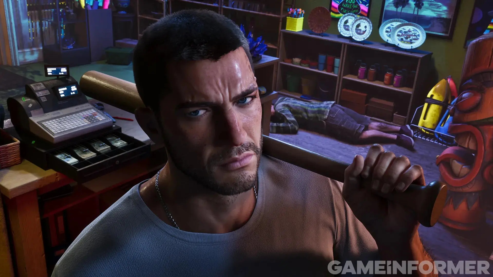 Jason, in a gray T-shirt, grips a baseball bat in a cluttered store next to the cash register.