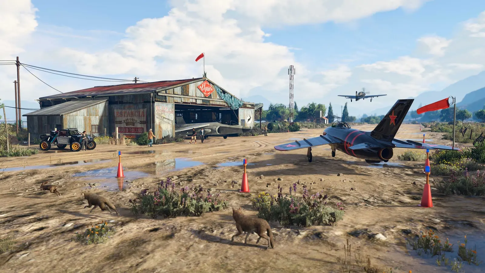 The McKenzie Field Hangar in Grapeseed in GTA Online, with prop planes, an off-roader and a jet parked and a coyote crossing the airstrip.